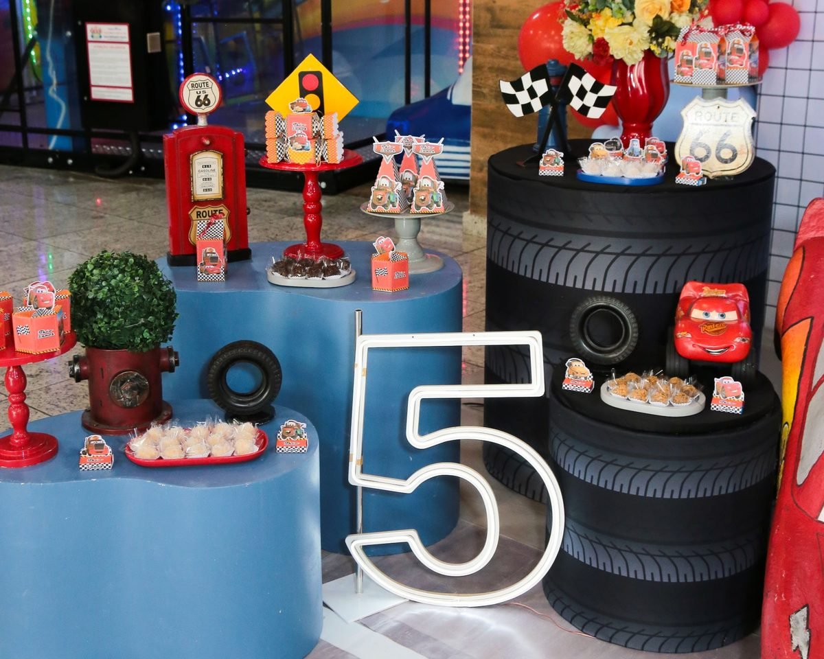 Mesa de doces no tema Carros, com bomba de gasolina, pneus, lembrancinhas personalizadas e o número 5 em neon
